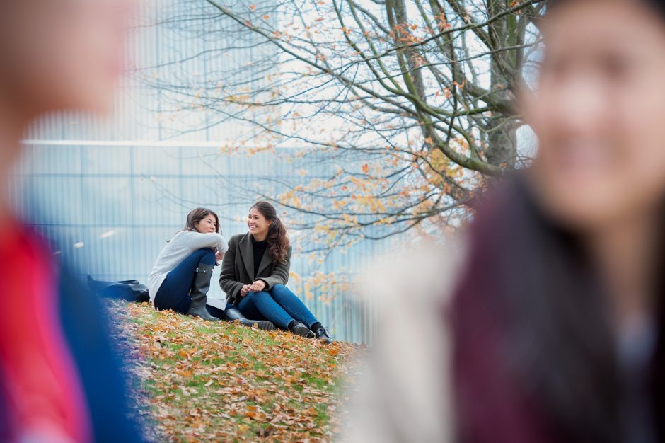 Two students seated on the grass during fall